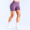 A person wearing purple seamless high-waisted yoga shorts and white athletic shoes.