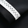 Close-up of a white, zigzag patterned sport arm sleeve on a black fabric background.