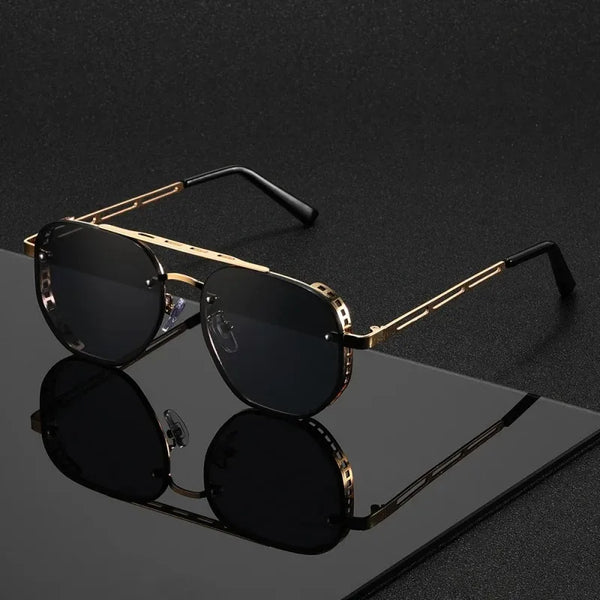 Gold-rimmed sunglasses with dark lenses resting on a black surface.