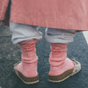 Pair of pink embroidered cotton socks worn with light gray pants and shoes.