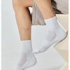 A close-up of white breathable sports performance socks being worn on a person's foot and ankle.