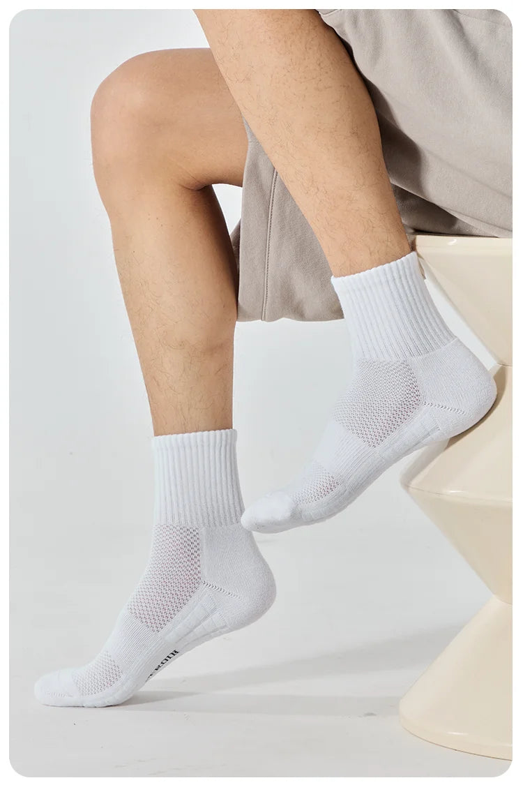 A close-up of white breathable sports performance socks being worn on a person's foot and ankle.