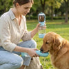 A woman feeds a dog using a 3-in-1 portable pet water and food dispenser.