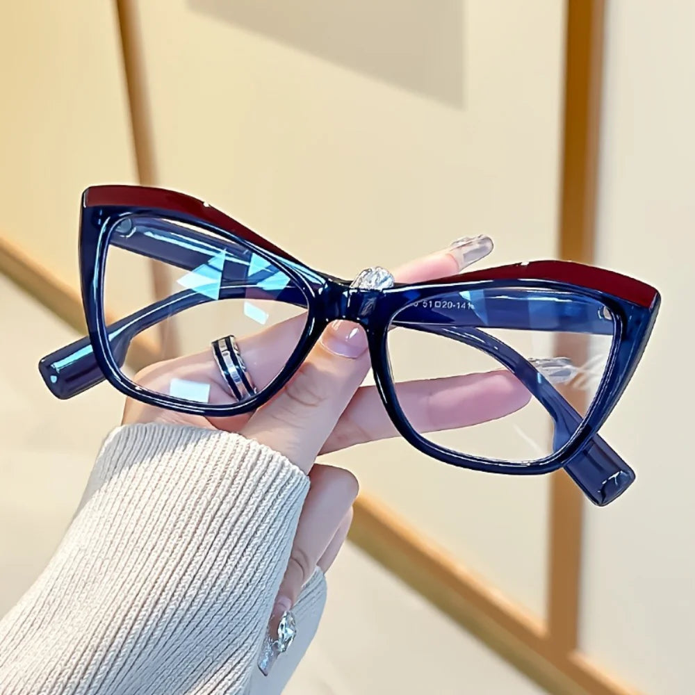 A hand holds a pair of vintage color block blue light blocking eyewear with dark frames and blue lenses.