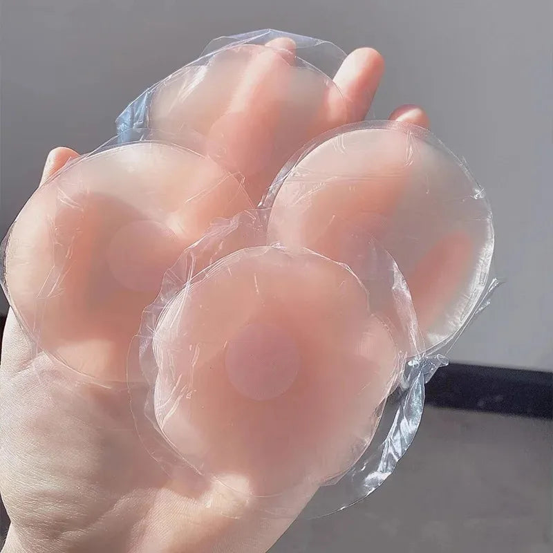 Une main tient un ensemble de cache-lèvres en silicone réutilisables, clairs et ronds.