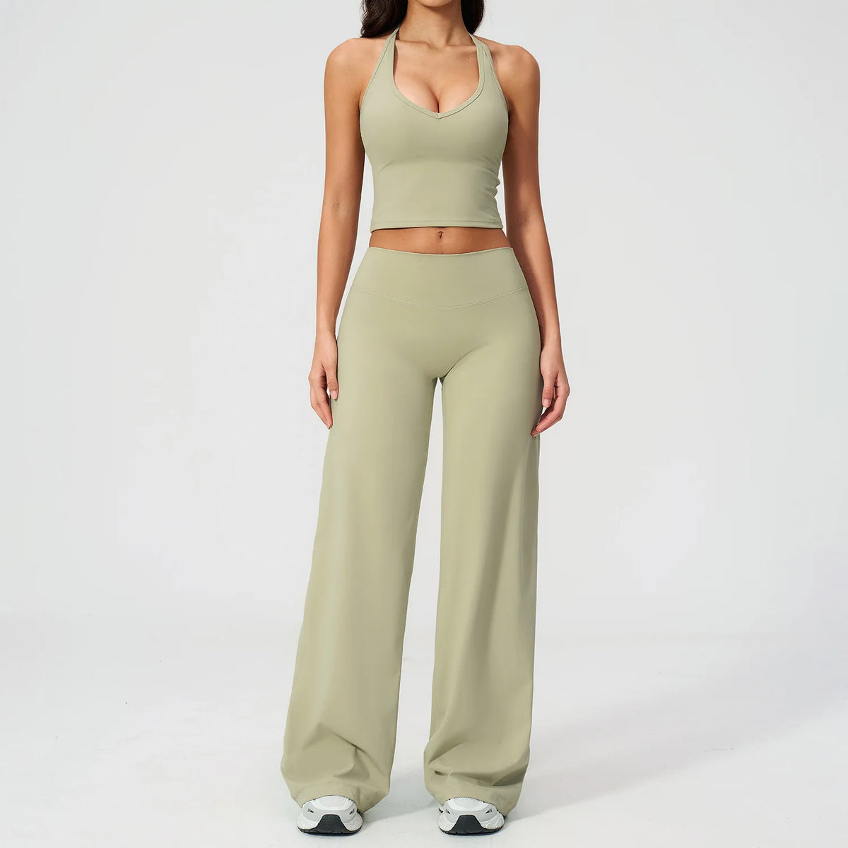 A woman wearing a light olive green women's premium fitness tracksuit top and matching pants.