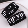 Schwarze Acryl-Elastik-Armbänder mit weißer VIP-Beschriftung auf einer weißen Platte.
