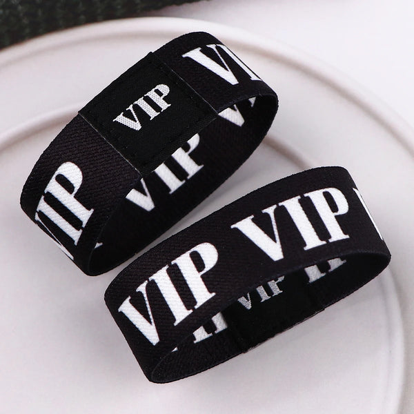 Black acrylic elastic rope bracelets with white VIP text displayed on a white plate.
