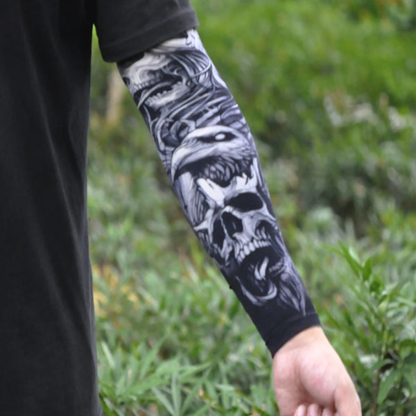 A person wearing a black shirt displays an arm covered in black and white skull tattoos on the sleeve.