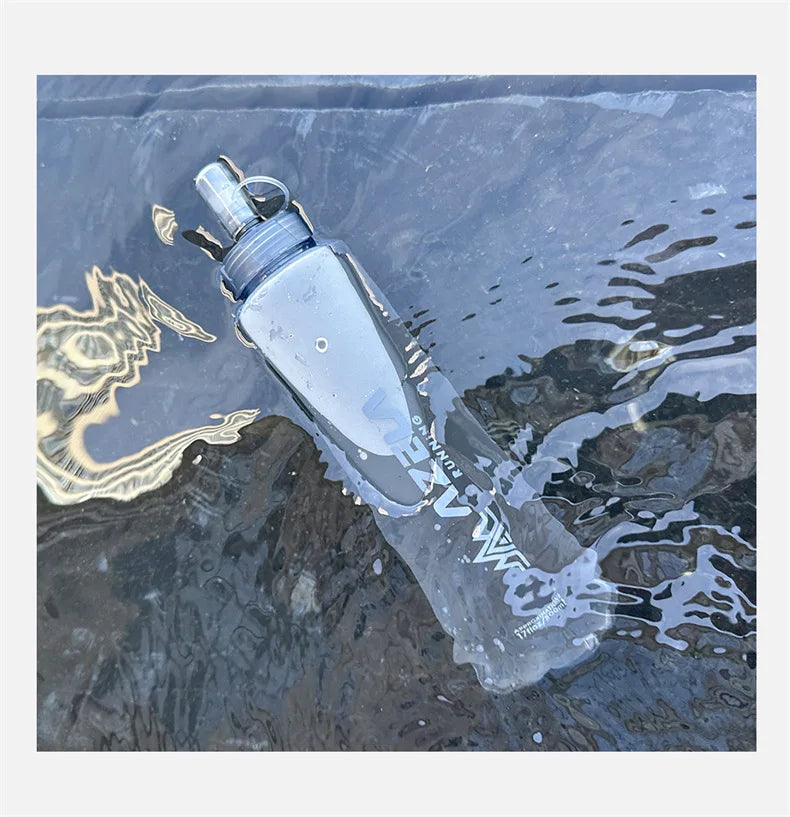 A clear silicone water bottle is submerged in dark water, showing its shape and texture.