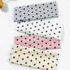 A set of four polka dot elastic hair bands in gray, white, pink, and beige are displayed on a white surface.