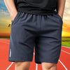 Navy men's quick dry jogging shorts worn by a person on an outdoor track.