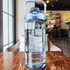 Una botella de agua aislada para viajar, transparente, con tapa y pajita azul, sobre una mesa de madera.