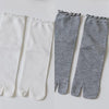 A pair of white and gray knit crew socks with ruffle cuffs shown flat.