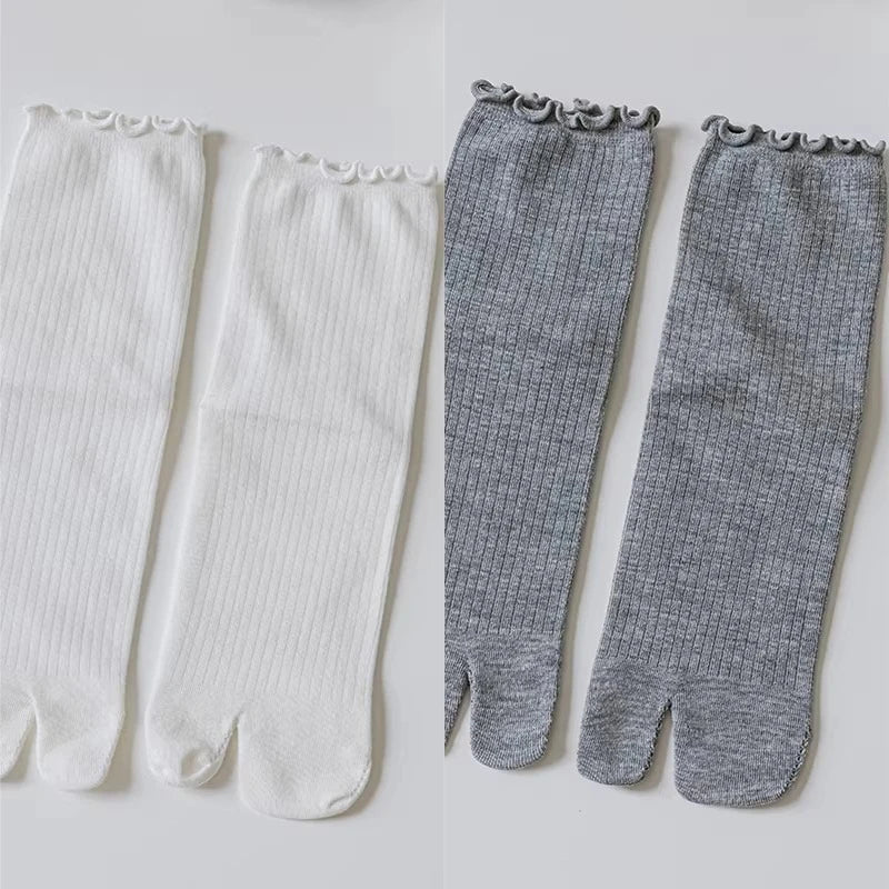 A pair of white and gray knit crew socks with ruffle cuffs shown flat.