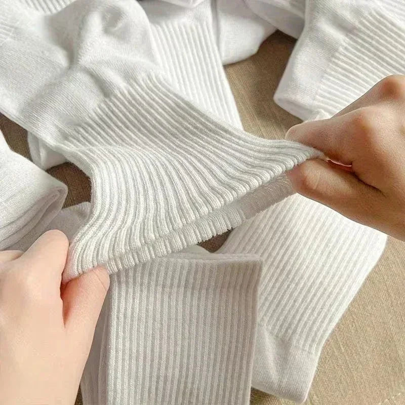 Gros plan de chaussettes en coton côtelé blanc portées sur une main et un pied.