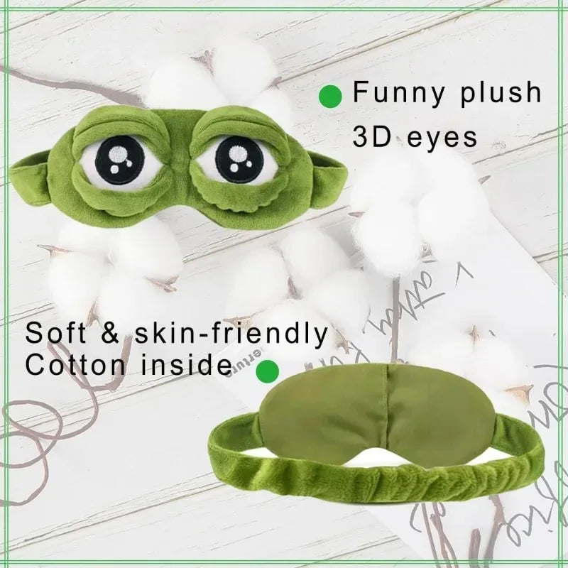 A green plush sleep eye mask with funny 3D eyes and soft cotton inside resting on a white surface.