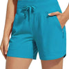 A woman is holding up a pair of teal high-waisted quick-dry athletic shorts.