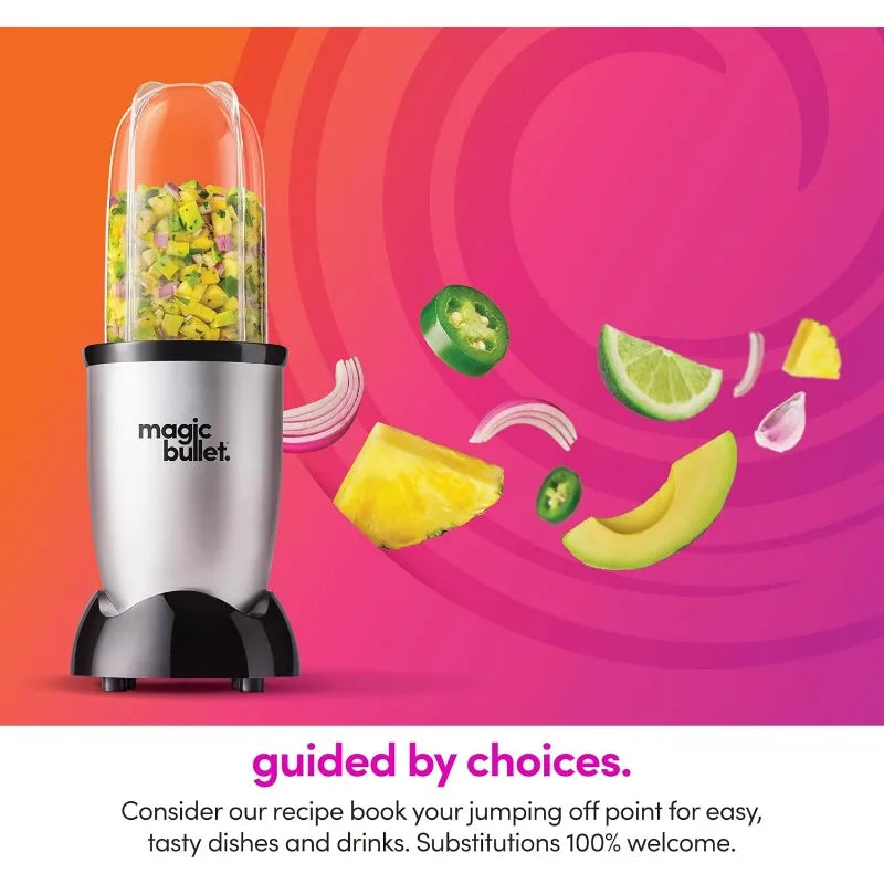 Licuadora Magic Bullet plateada con trozos de fruta y verdura volando sobre un fondo rosa.
