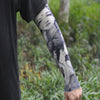 A person wearing a black garment is displaying an arm with a black and white ice silk tattoo sleeve.