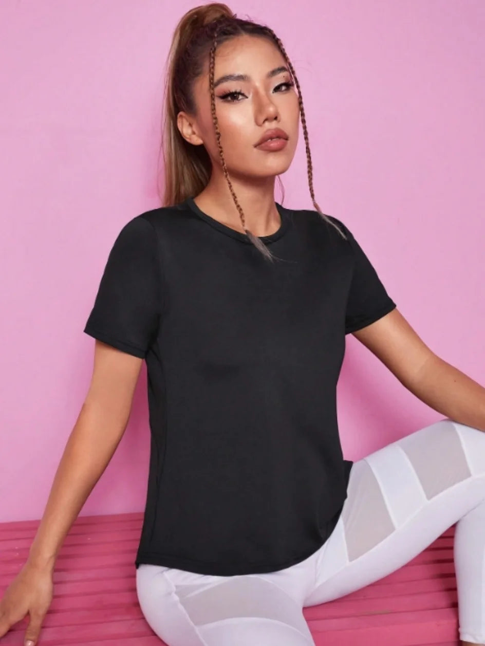 A woman models a black breathable summer yoga and fitness t-shirt while sitting down.