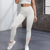 Une femme portant des leggings de yoga tricotés unis blancs et un haut court devant un mur de briques.