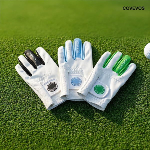 A set of three white golf gloves in black, light blue, and green colors resting on a green golf course surface.