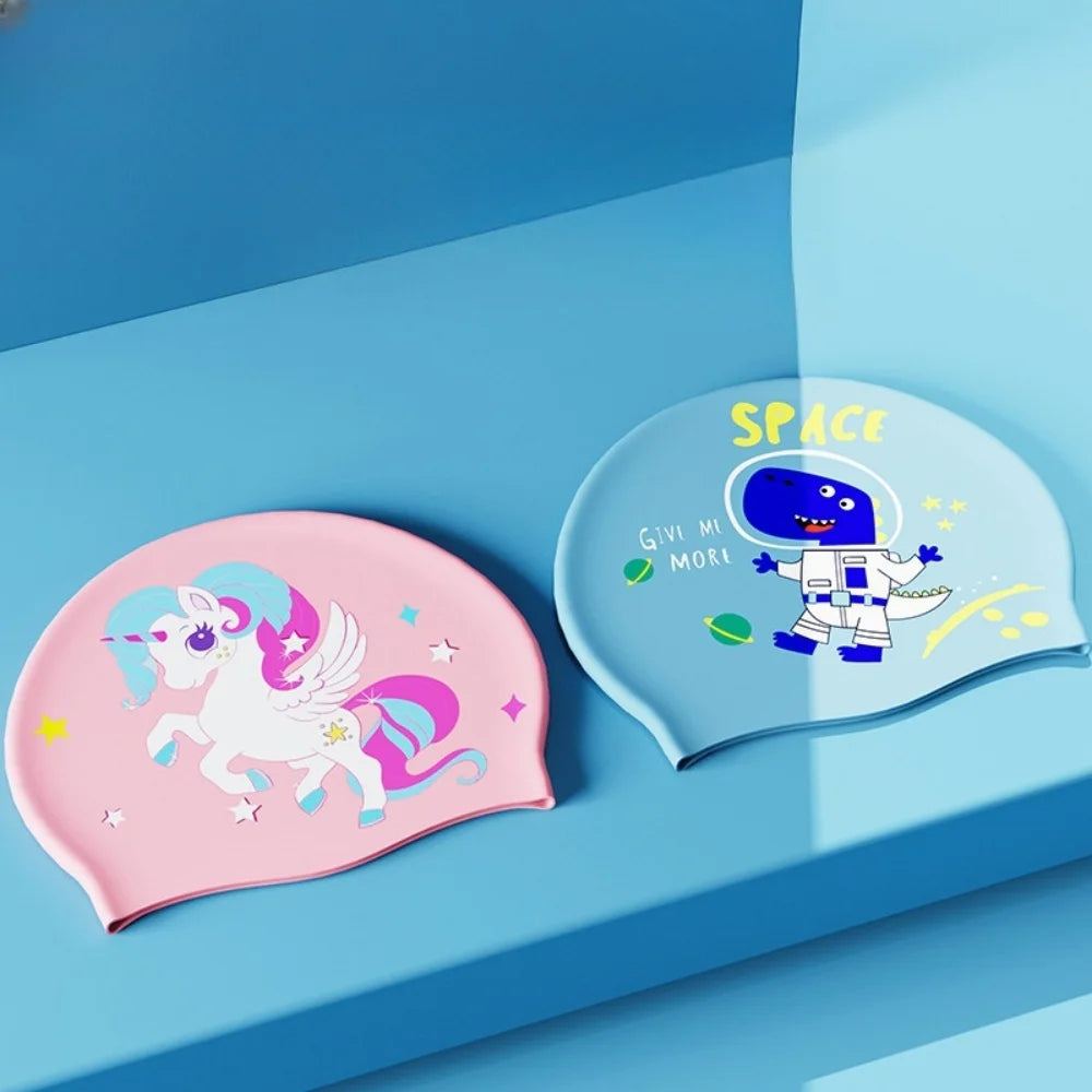 Two silicone swimming caps featuring a unicorn and a space theme are displayed on a blue surface.
