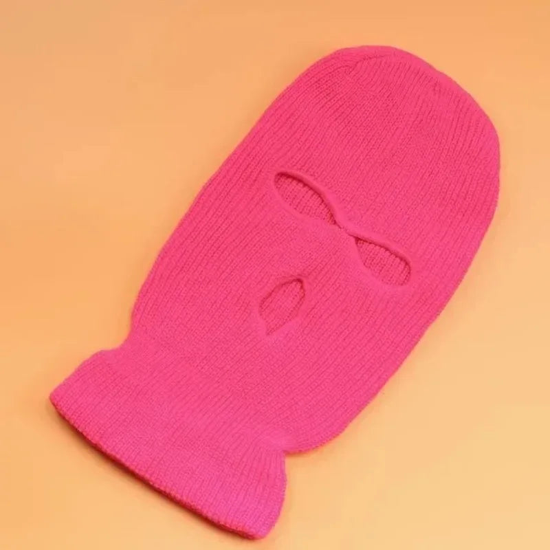 A bright pink tactical knit balaclava beanie hat shown against a light orange background.