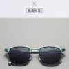 A pair of teal-framed sunglasses with dark lenses shown against a light gray background.