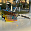 A pair of orange-tinted sports sunglasses resting on a white surface outdoors.