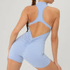 A woman wearing a light blue, backless fitness jumpsuit.