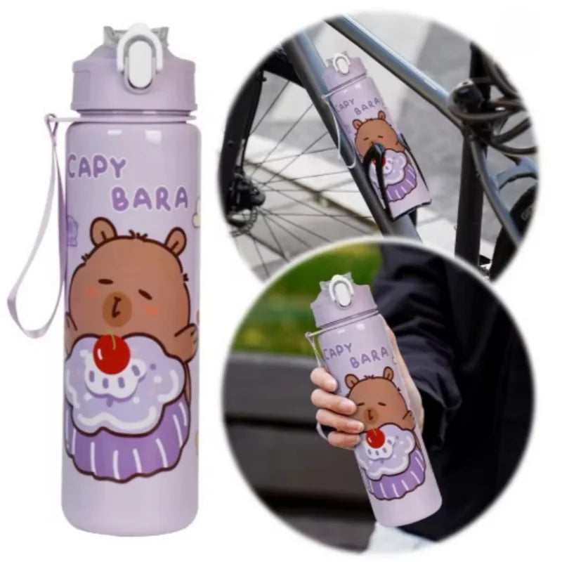 A cute purple capybara water bottle with a straw and handle is shown next to a bicycle wheel.