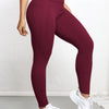 A woman wearing maroon high-waisted sports leggings and white sneakers.