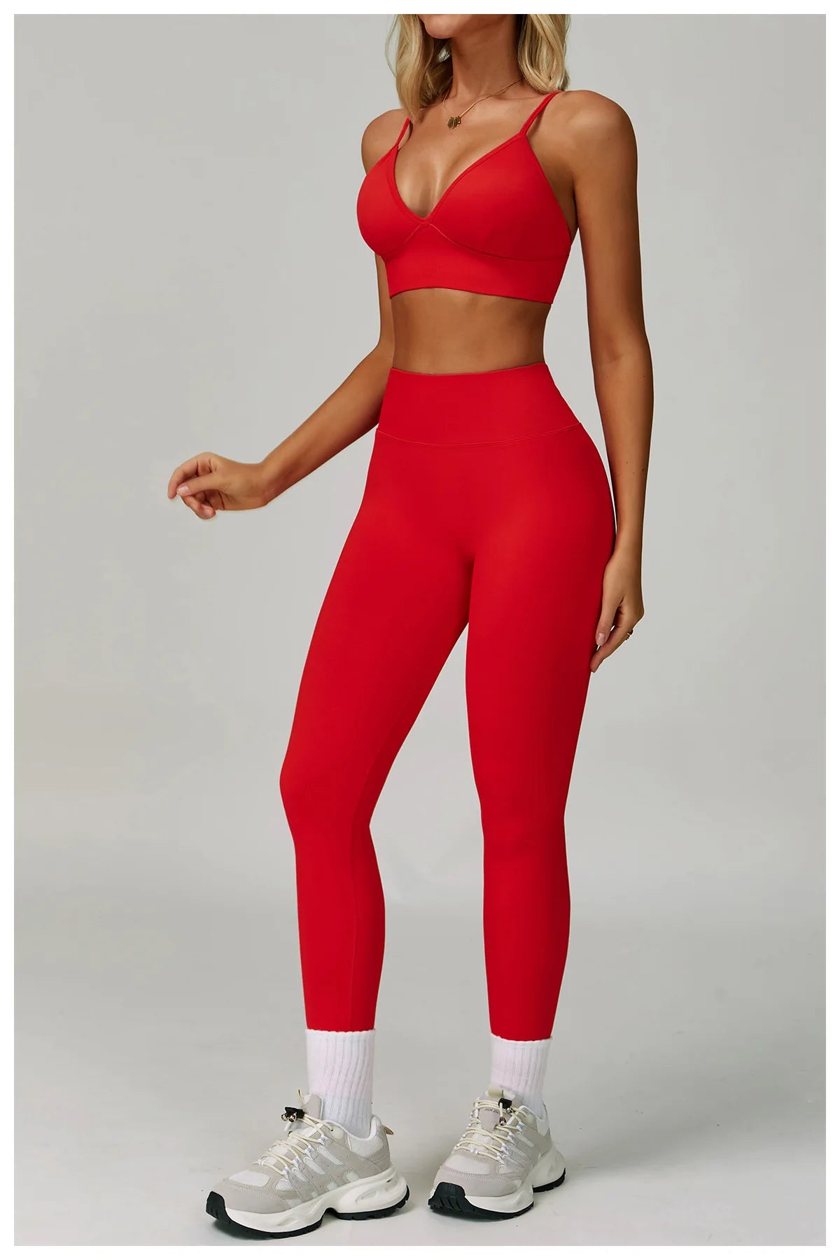 Eine Frau modelliert ein rotes, nahtloses Sport-Yoga-Set mit Crop-Top und Leggings.