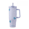 A white insulated thermos mug with a light purple hue decorated with heart-shaped pearl inlays.