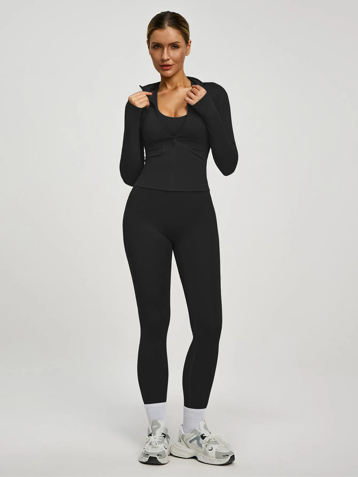 Eine Frau modelliert ein schwarzes Zweiteil-Yoga-Sportset mit langärmeligem Oberteil und Leggings.