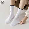 A pair of white crew socks with a smiling face design being held by a person's hand.
