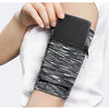 A hand is holding a black zippered wrist bag with a black phone inside, featuring a black and white striped pattern.