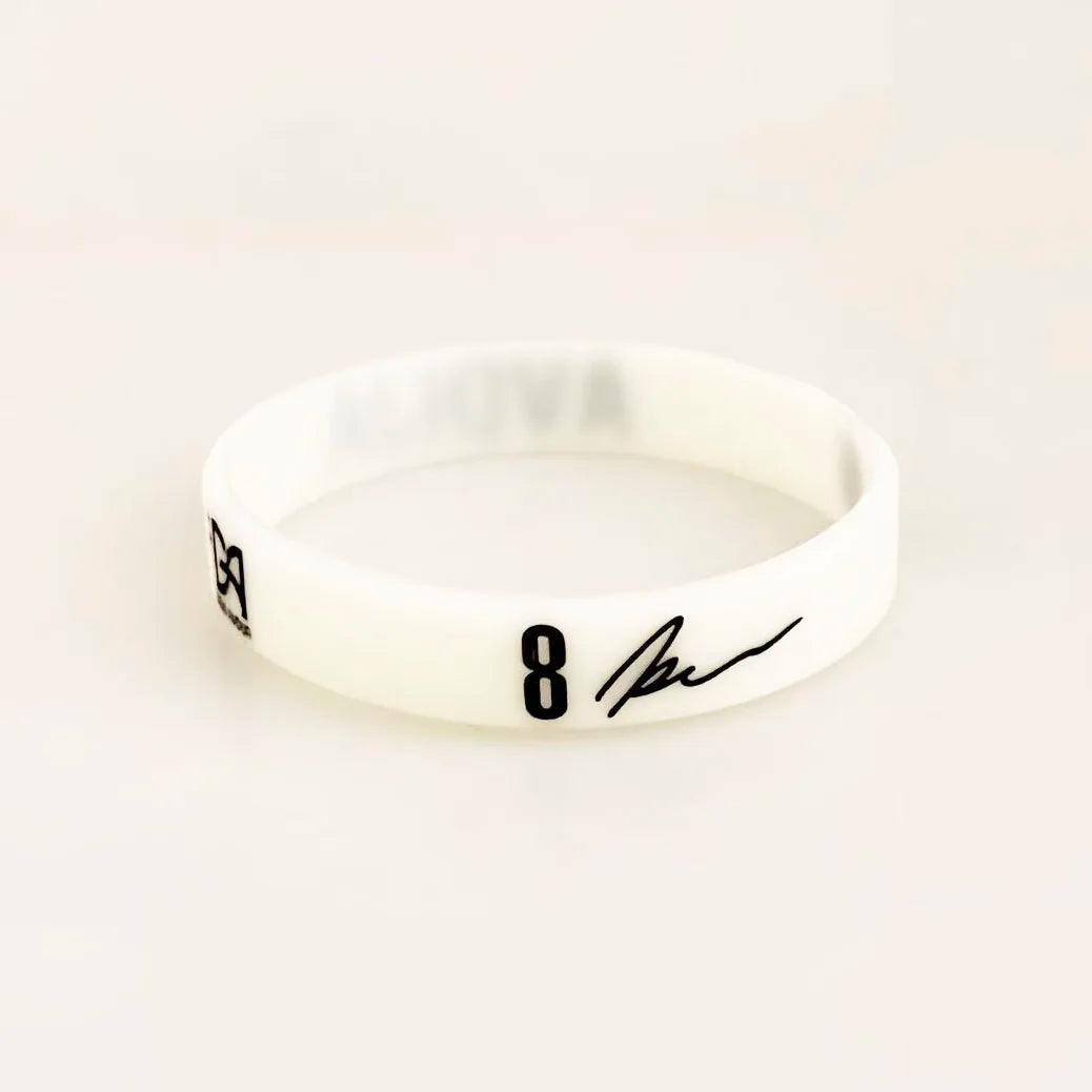 A white silicone wristband with black text showing the number 8 and a signature.