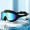 Black anti-fog UV protection swimming goggles resting on a white marble surface with blue water background