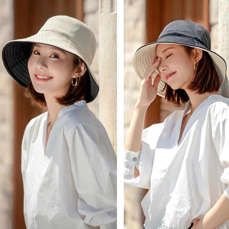 A woman wearing a wide brim bucket hat and a white shirt outdoors.