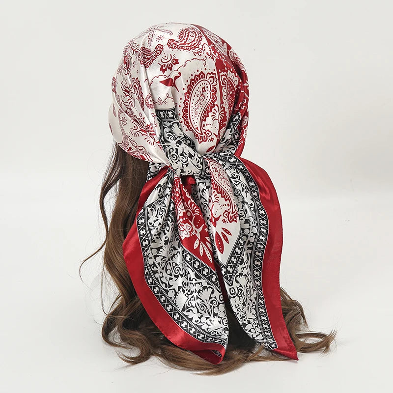 A red and white patterned satin square scarf tied around a dark brown hair