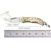 A brass folding knife keychain with a silver blade and decorative handle, shown next to a ruler.