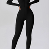 Eine Frau in einem schwarzen Zip-Jumpsuit für Yoga und weißen Sneakern.