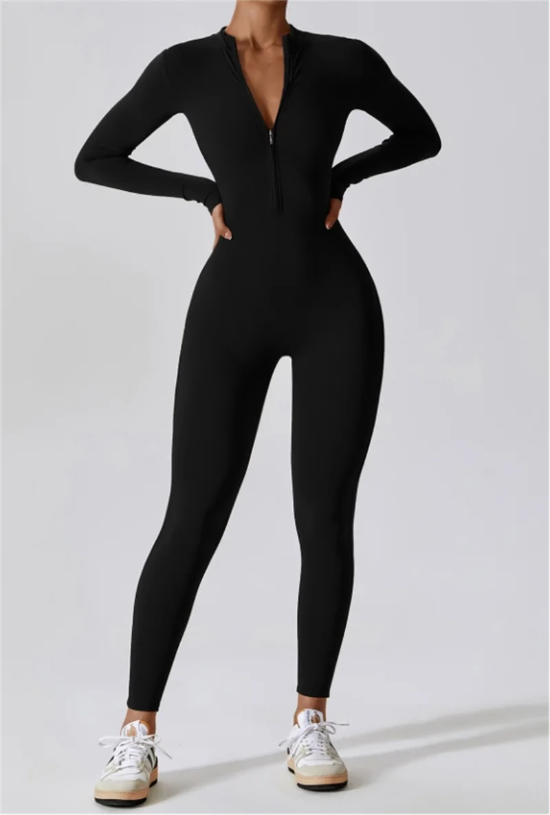 Eine Frau in einem schwarzen Zip-Jumpsuit für Yoga und weißen Sneakern.