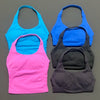 Vier nahtlose Strick-Sport-Tanktops in leuchtendem Blau, Pink und Grau vor grauem Hintergrund.