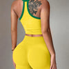 A woman wearing a yellow yoga set featuring a racerback tank top and matching shorts.