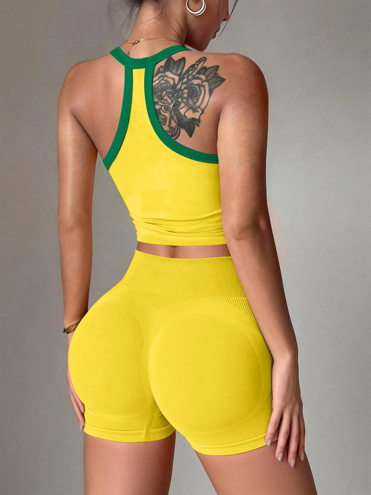 A woman wearing a yellow yoga set featuring a racerback tank top and matching shorts.
