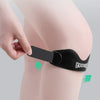 A hand is applying a black silicone patellar strap for knee support to a person's knee.
